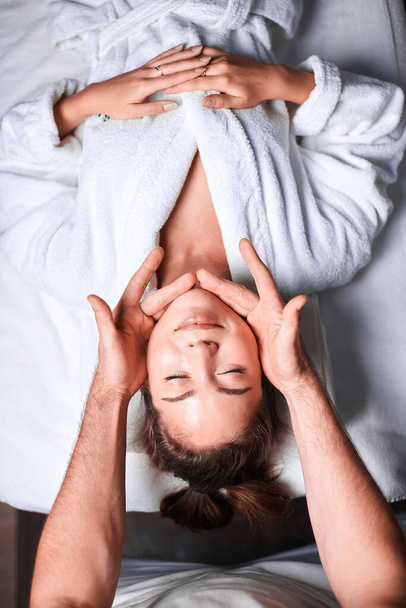 Woman enjoying anti aging facial massage. Upside down photo of relaxing woman - Foto, afbeelding