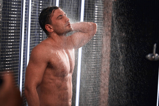 Handsome man taking shower, refreshing himself after a hot working day. - Zdjęcie, obraz