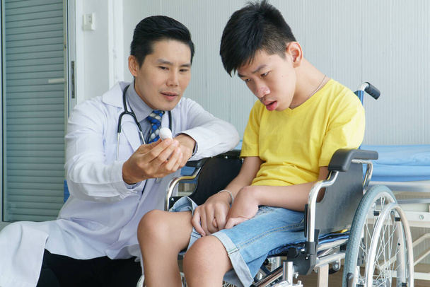 Ázsiai orvosok, felnőtt férfiak, akik mozgássérült fiúkkal beszélgetnek. Rokkantsági tanácsadás és rehabilitáció kórházakban. Technológia és modern orvostudomány - Fotó, kép