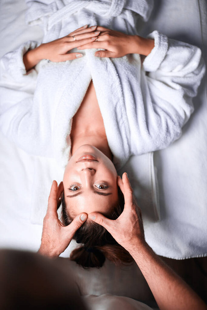 Woman enjoying anti aging facial massage. Upside down photo of relaxing woman - Φωτογραφία, εικόνα