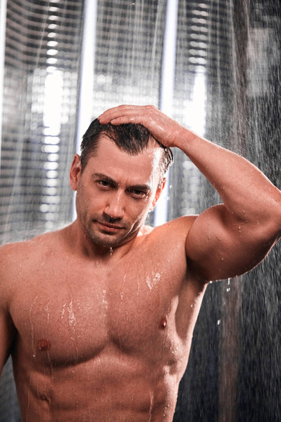 Handsome man taking shower, refreshing himself after a hot working day. - Photo, Image