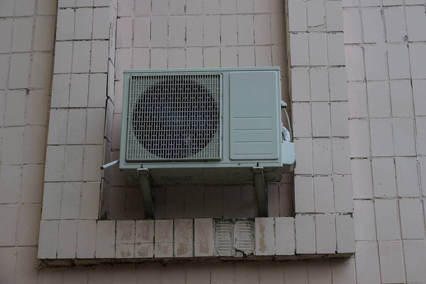 un gran acondicionador de aire gris colgando en una pared de edificio marrón exterior
 - Foto, imagen