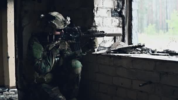 Soldado em camuflagem com uma arma militar apontando através da mira do rifle através da janela de um edifício velho. - Filmagem, Vídeo