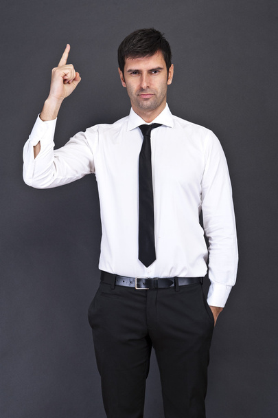 Young businessman criticizing on gray background - Photo, Image
