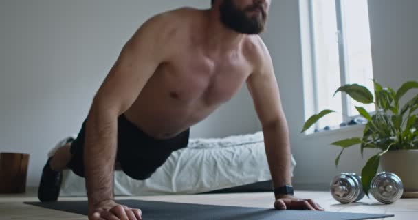 Shirtless guy exercising push ups on floor at home, close up - Video