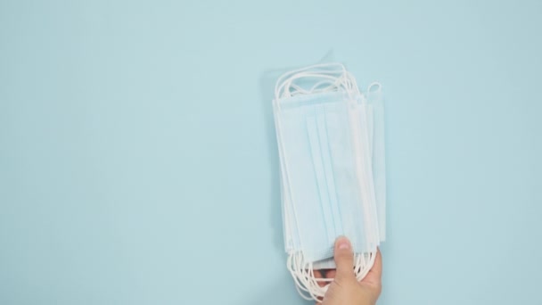 female hand puts a disposable medical mask and a reusable textile mask on a blue background. The concept of avoiding materials that pollute the environment, top view - Metraje, vídeo