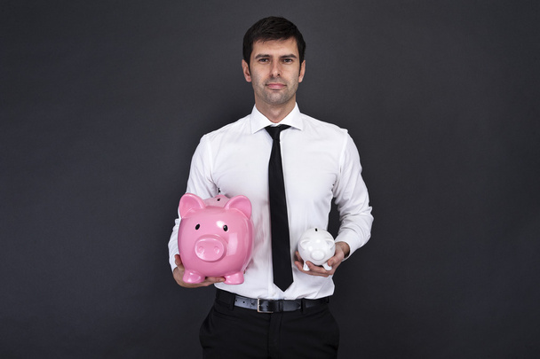 Portret van een jonge man met een twee piggy bank tegen een grunge - Foto, afbeelding