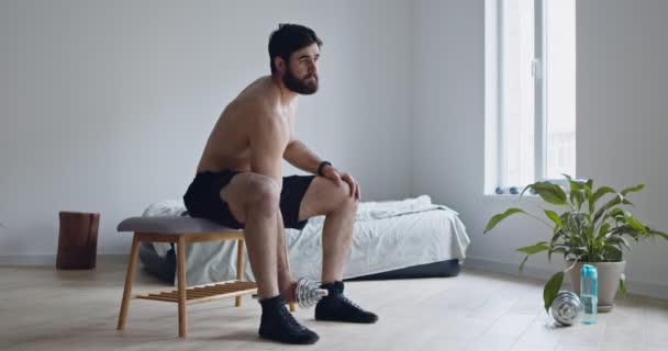 Mladý muž s nahým trupem zvedající činku doma - Záběry, video