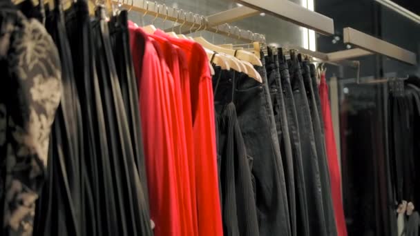 Appendini con abiti, pantaloni e camicie nel negozio di abbigliamento - Filmati, video