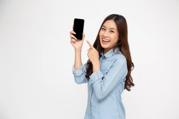 Porträt einer Asiatin, die ihre Handy-Anwendung zeigt oder präsentiert und mit dem Finger auf ihr Smartphone zeigt, isoliert auf weißem Hintergrund, asiatisches thailändisches Modell - Foto, Bild