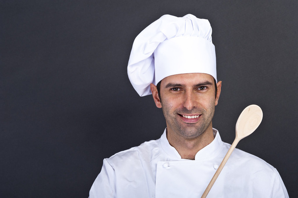portriat of the cook with spoon over dark background - Photo, Image
