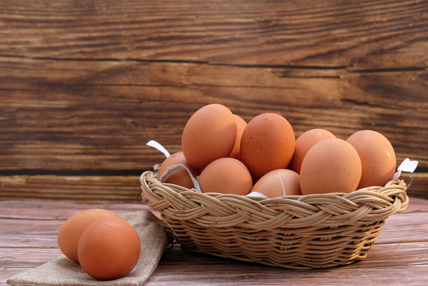 Chicken eggs in basket on wood table background and space for text - Photo, Image