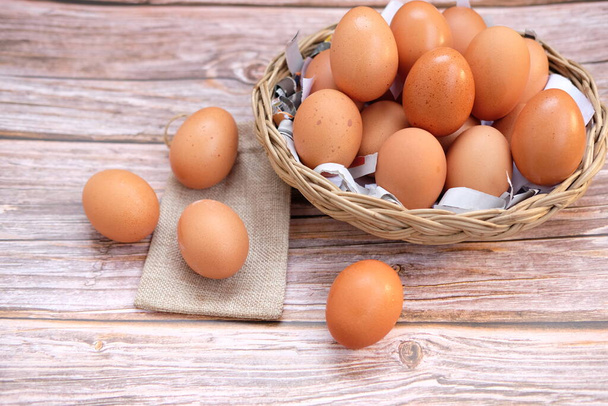 Kuřecí vejce v košíku na dřevěném stole pozadí a prostor pro text - Fotografie, Obrázek