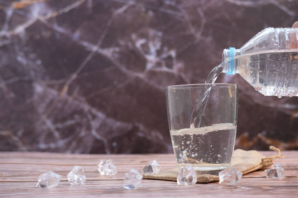 versando acqua potabile in bicchieri su fondo tavolo in legno e spazio per il testo - Foto, immagini
