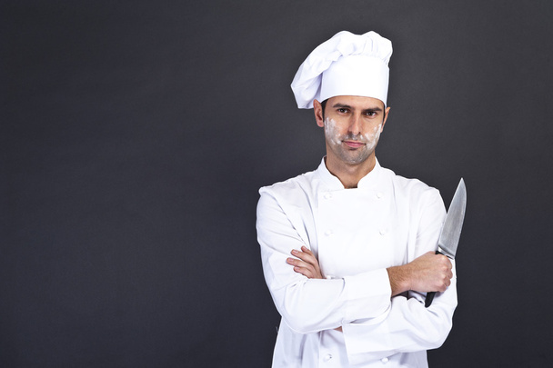 Porträt eines jungen Kochs in Uniform, der ein Messer hält - Foto, Bild