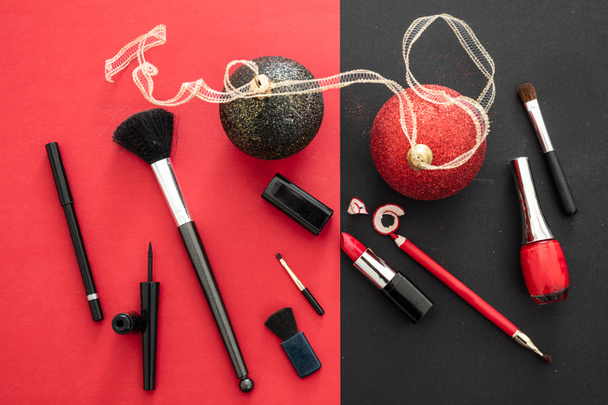 Make-up xmas party concept, rode en zwarte platte achtergrond. Make-up producten en kerstballen, Oudejaarsavond voorbereiding - Foto, afbeelding