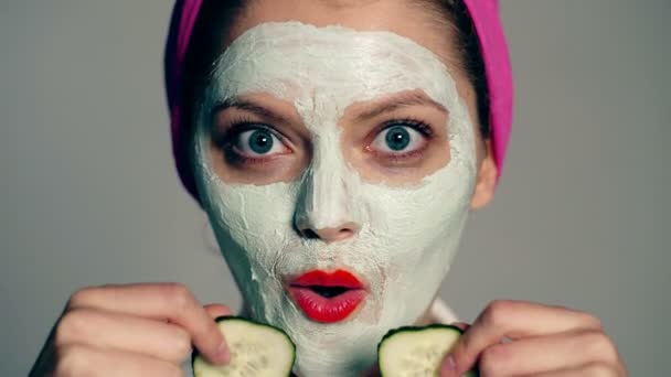 Close up of girl with mask on her face that closes her eyes with cucumbers and smiles. Woman wearing face mask. Face care, facial concept. - Πλάνα, βίντεο