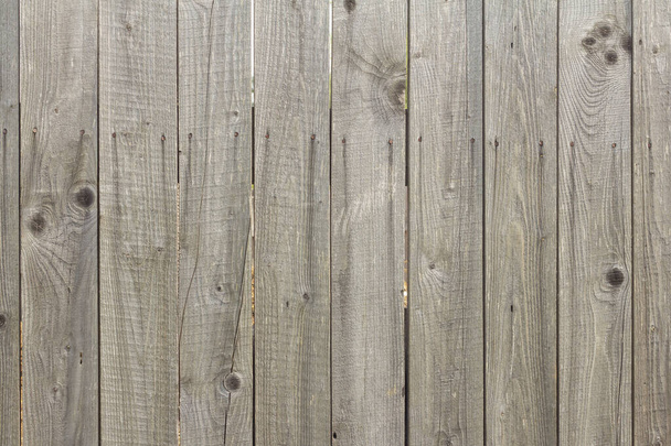 Holzhintergrund in Naturgrau. Alter rustikaler Zaun mit Rissen und rostigen Nägeln - Foto, Bild