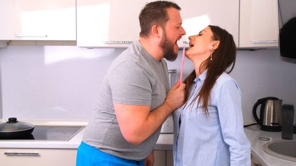 Atraente jovem casal alegre homem e mulher se divertir dançando e cantando enquanto cozinha na cozinha em casa
. - Foto, Imagem