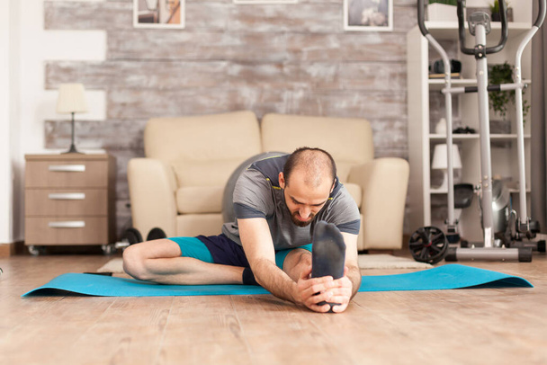 Atletische man stretching uit voor de training - Foto, afbeelding