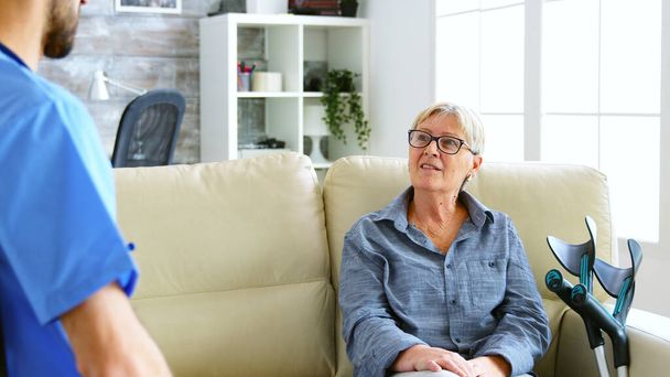 Senior idosa sentada no sofá em casa de repouso conversando com o médico
 - Foto, Imagem