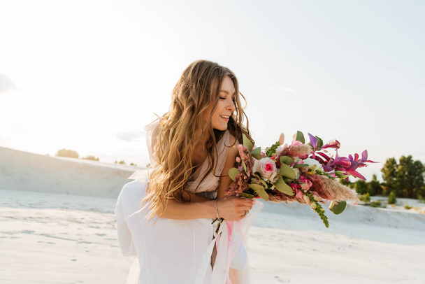 Love Story of a beautiful couple in a pink wedding luxury dress with a bouquet in the Sahara desert, sand, dunes - 写真・画像