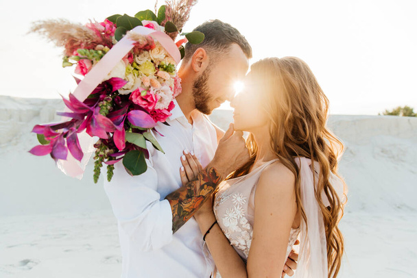 Love Story of a beautiful couple in a pink wedding luxury dress with a bouquet in the Sahara desert, sand, dunes - Photo, Image
