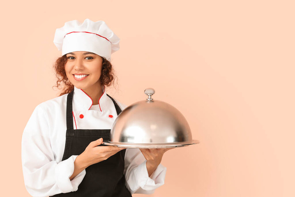 Cuoca afro-americana con vassoio e cloche su sfondo a colori - Foto, immagini