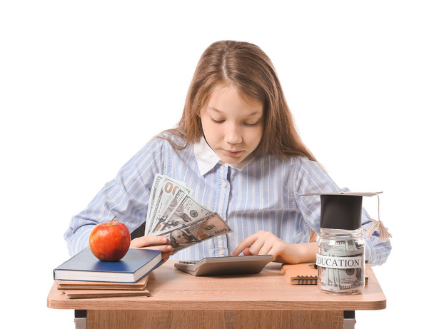 Dziewczyna z oszczędności na edukację i kalkulator siedzi przy biurku na białym tle - Zdjęcie, obraz