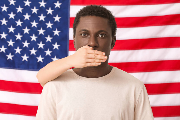 Personne couvrant la bouche du triste homme afro-américain près du drapeau national des États-Unis. Arrêtez le racisme - Photo, image