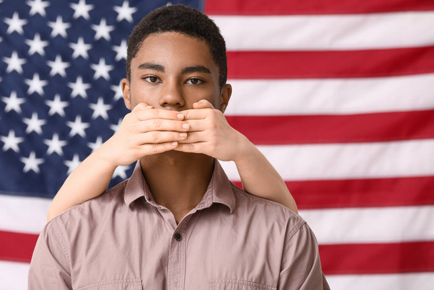 Personne couvrant la bouche d'un adolescent afro-américain triste près du drapeau national des États-Unis. Arrêtez le racisme - Photo, image