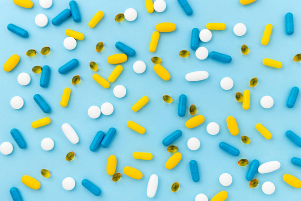 Bunte medizinische Pillen auf blauem Hintergrund. Von oben flach lagen biologisch aktive Nahrungsergänzungsmittel. Behandlungskonzept im Gesundheitswesen - Foto, Bild