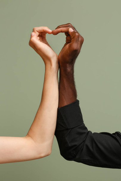 Mulher caucasiana e homem afro-americano fazendo coração com as mãos no fundo de cor. Conceito de racismo
 - Foto, Imagem