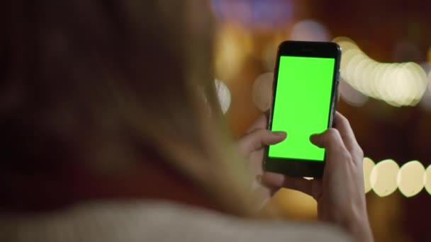 電話の緑の画面を使用してバックビューの女の子。外でモックアップ電話を使用して女性の手 - 映像、動画