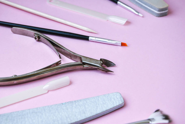 ピンクの背景にマニキュアとペディキュアツール。ネイルサロンバナーデザインテンプレート。美容治療の概念。テキストのコピースペース - 写真・画像