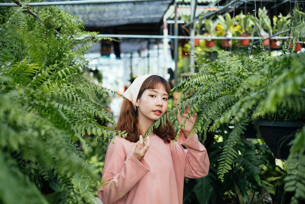 Gardener girl looking at her fern in a glasshouse to check a moistness. - Photo, Image