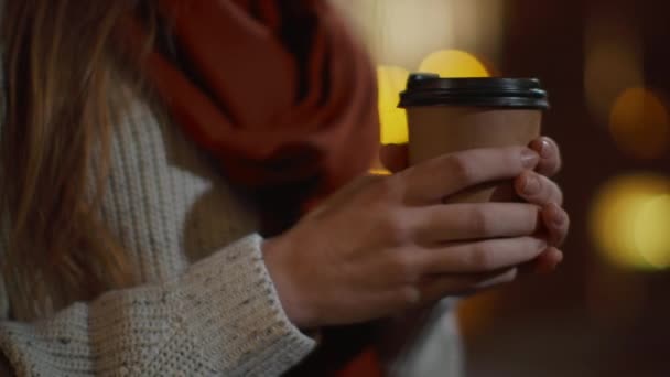 紙コップを屋外に持っている女の子の手。外でコーヒーを飲んでいる無名の女性 - 映像、動画