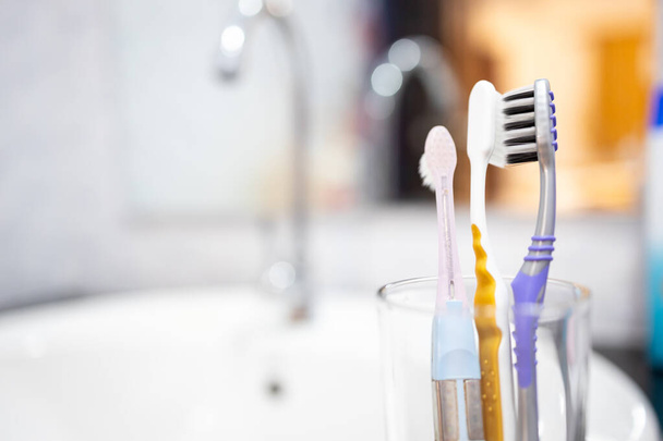 Tandenborstels worden dicht bij elkaar gehouden in de bril, voorkomen dat tandenborstelkoppen dicht bij elkaar worden gehouden, gescheiden zijn van elkaar, de verspreiding van COVID-19, pandemie van Coronavirus ziekte, nieuw normaal concept voorkomen - Foto, afbeelding