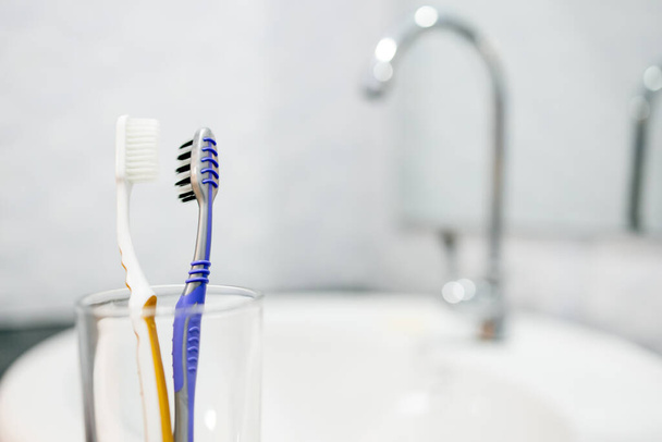 Tandenborstels worden dicht bij elkaar gehouden in de bril, gebruikte tandenborstels moeten worden gescheiden in veiligheid, voorkomen dat de verspreiding van COVID-19, besmettelijke ziekte, pandemie van het Coronavirus, Houd afstand, nieuwe normale - Foto, afbeelding