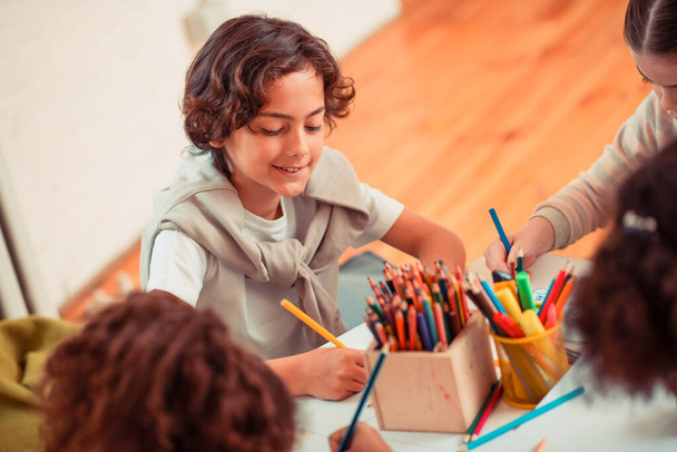 Натхненний хлопчик малює кольоровими олівцями в класі
 - Фото, зображення