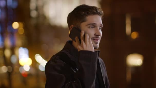 Un hombre alegre contestando una llamada en la calle. Chico guapo hablando teléfono móvil
. - Metraje, vídeo