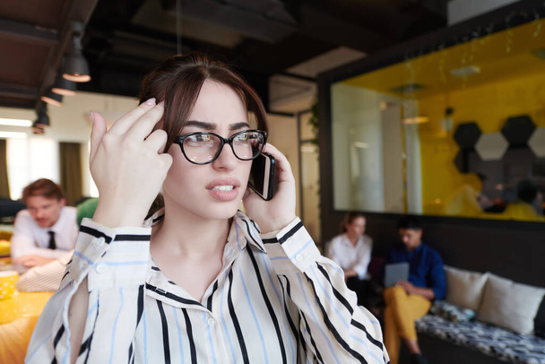businesswoman with glasses using mobile phone at modern startup open plan office interior - Zdjęcie, obraz