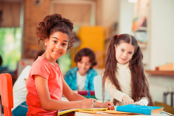 Smiling girl doing her homework together with her classmate - Zdjęcie, obraz