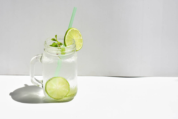 Copo Mason jar de limonada com fatia de limão verde e folha de hortelã, mel isolado em um fundo branco, bebida de verão, fresco, bebida, caseiro, fresco, suco de frutas, vista lateral
 - Foto, Imagem