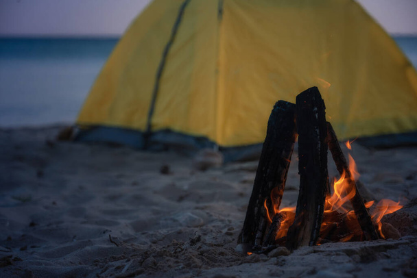 Closeup Fogo em fogueira na praia. Acampar e tendas para viajar. Acampamento noturno na costa do mar
. - Foto, Imagem