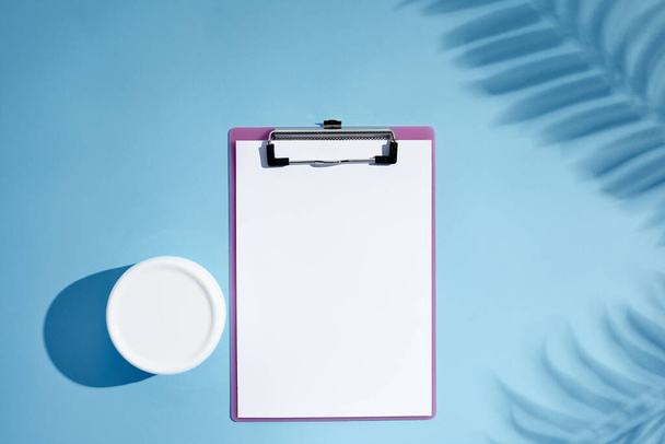 blank cosmetics jar and empty clipboard with palm shadows - Foto, afbeelding
