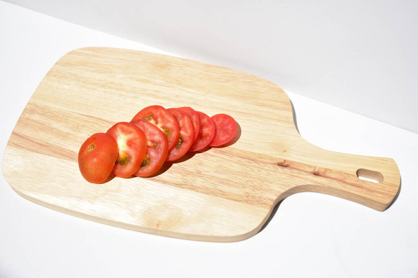 木製のまな板上のトマトスライス孤立した、白い背景、木製のまな板、料理、健康的な食べ物、体重を減らす、ビーガン料理、キッチン、日当たりの良い - 写真・画像