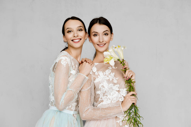 Two beautiful girls in transparent tulle dresses with lace posing in identical manner - Fotografie, Obrázek