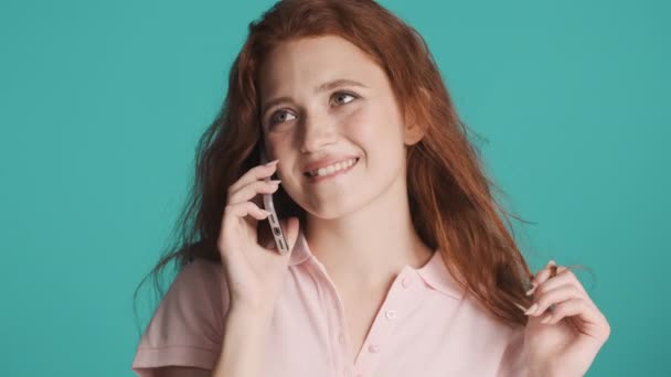 Beautiful charming redhead girl happily talking on phone over colorful background. Cute girl posing - Materiał filmowy, wideo