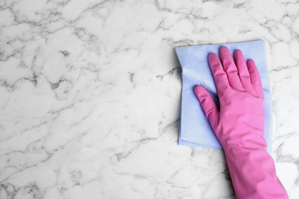 Woman in gloves wiping white marble table with rag, top view. Space for text - Photo, Image